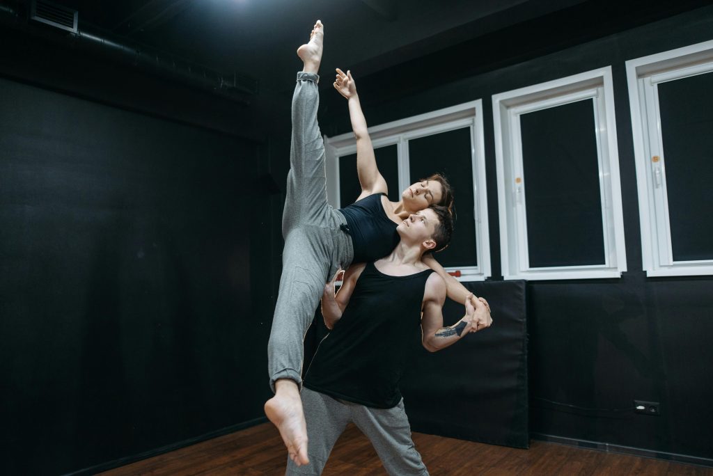 A man and woman practice contemporary dance moves in a studio, showcasing flexibility and strength.